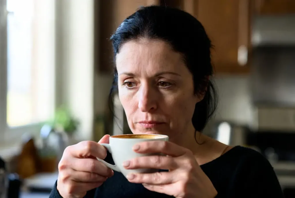 ondas de calor na menopausa — mulher segurando xícara de café em momento de atenção ao próprio corpo
